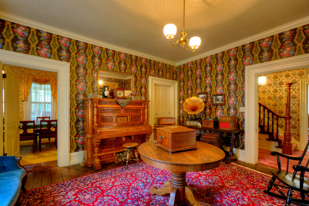 The east parlor, located across the front foyer from the west parlor, is decorated with Schumacher silk-screened wallcoverings. Off the parlor, as well as the kitchen, is the dining room, which can be seen in the left of the picture.